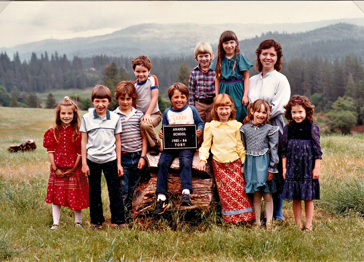Teacher Narani Moorehouse with her students 1983-84 posed on a hillside at Ananda Village.