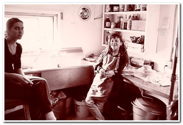 Two girls in aprons rest in the pizza kitchen at Master's Market at Ananda Village.