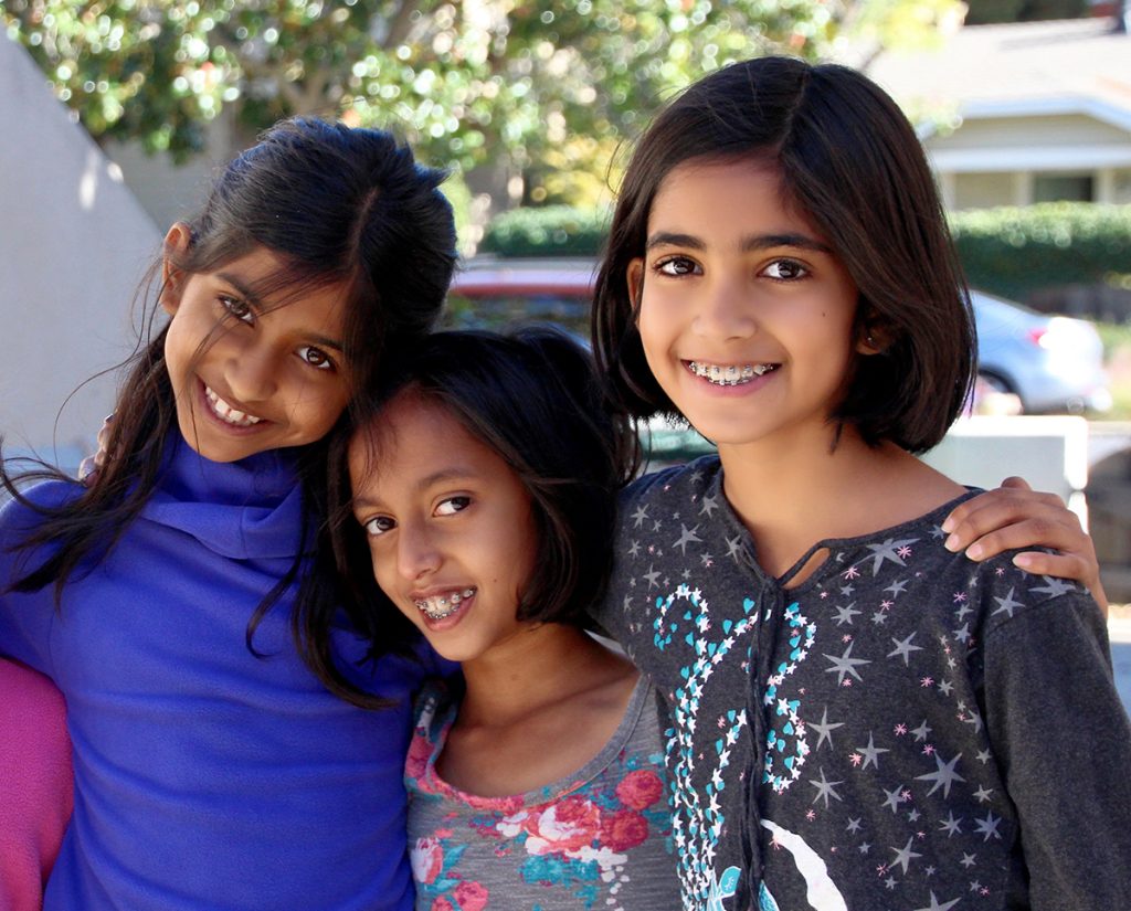 Three young girls pose together at Living Wisdom School of Palo Alto, California.