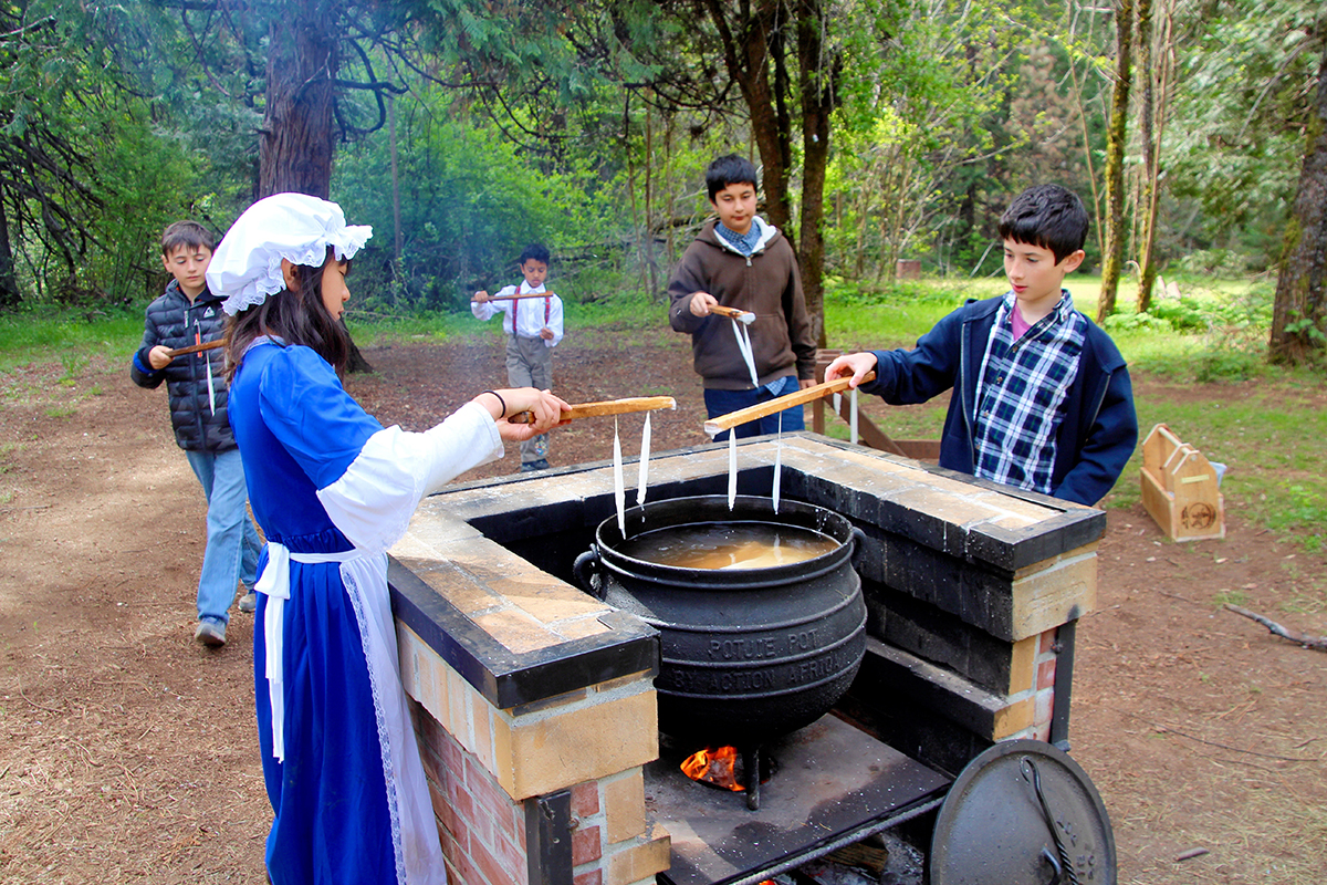 Kids in Gold Rush era costumes dip candles at Malakoff Diggins State Park during a campout in the Sierra Nevada mountains of northern California.
