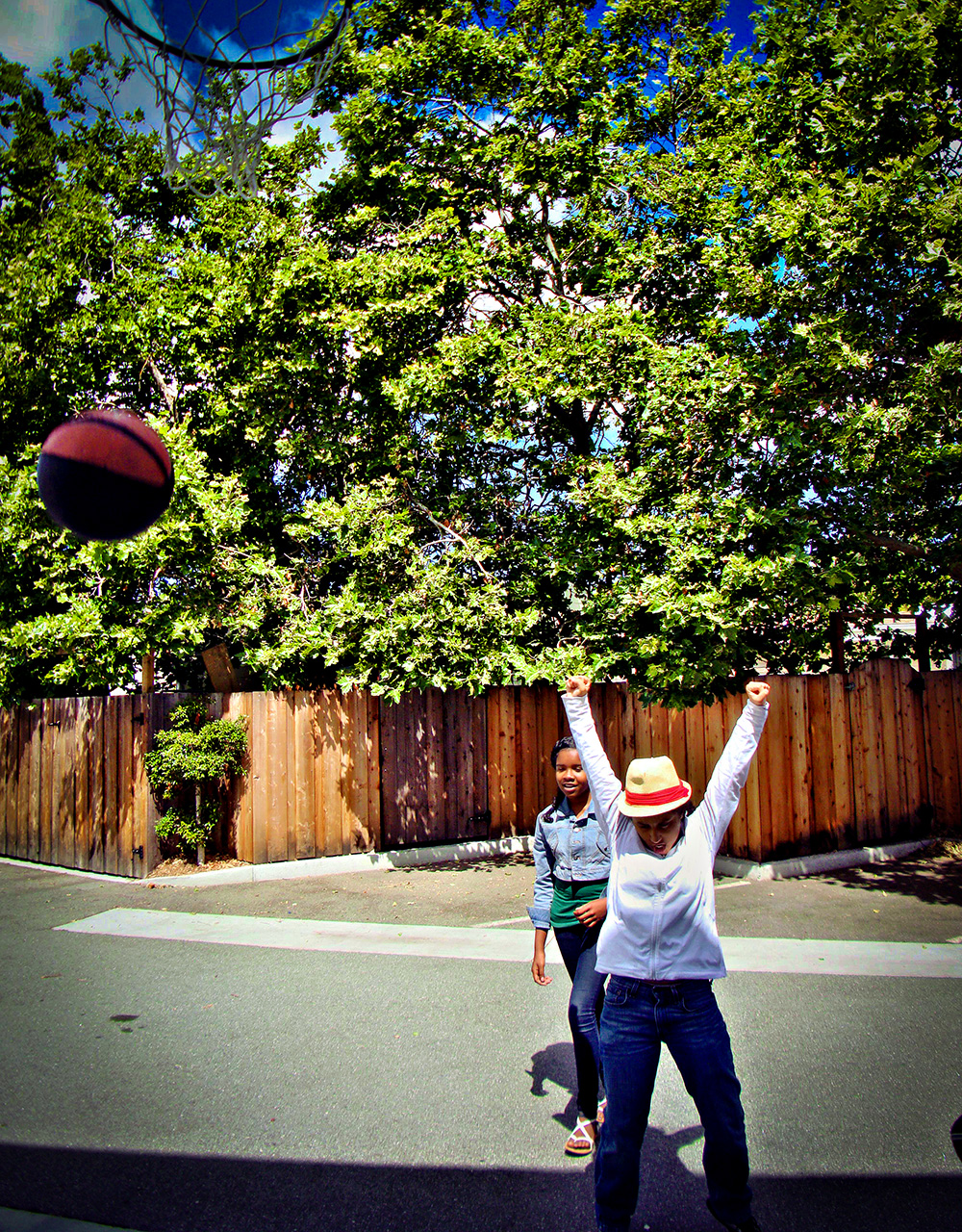 Middle school girl raises arms in victory as basketball falls through the hoop.