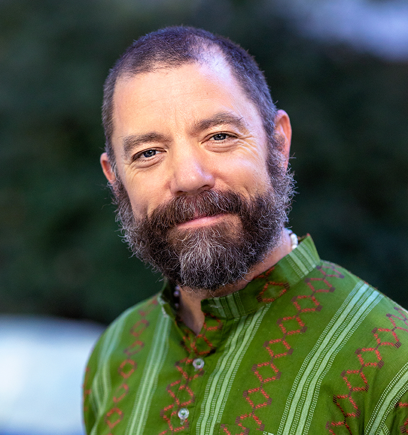 Martial arts instructor and PhysEd teacher David James, portrait photo taken outdoors wearing green Gandhi collar shirt and smiling.