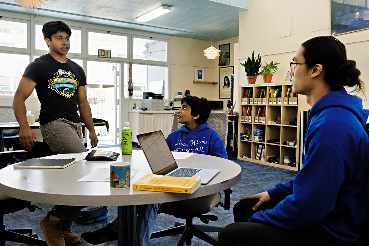 Hari (left) and Kanha chat with teacher Haze (pron. Haahzie) before an Advanced Math tutoring class. At this writing, Hari was training to improve his deadlift one-rep max to 500 pounds. Teacher Haze, a world-class mathematician, began practicing martial arts at age three and has won multiple titles including a World Championship at 14; he has also competed as a member of the USA Senior National Karate Team. Photo by the author.