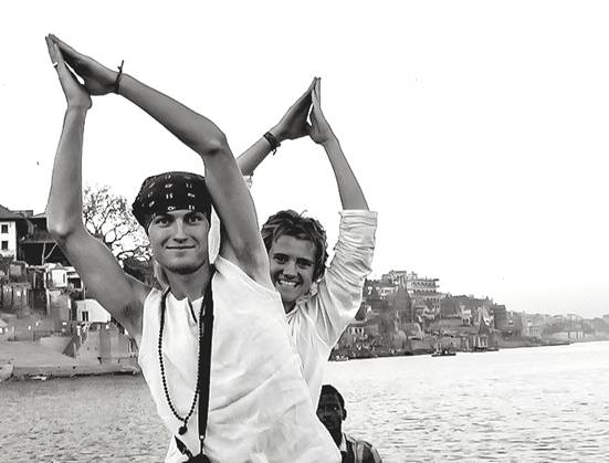 Two American boys ride in boat on Ganges while holding hands joined above their heads during a service adventure trip by students of Living Wisdom High School in Palo Alto, California.