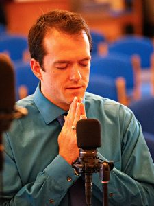 Keshava in green shirt and tie, pronams to the audience after singing a solo at a concert of Swami Kriyananda's oratorio, "Christ Lives."