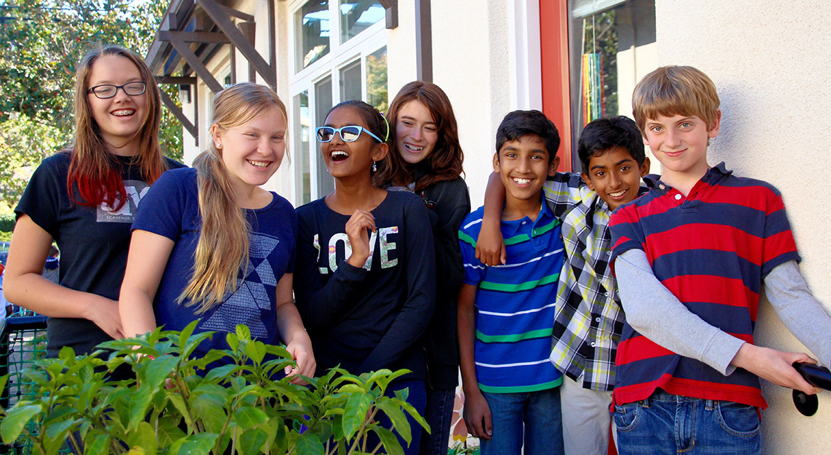 Middle schoolers outdoors laugh and joke for the camera.