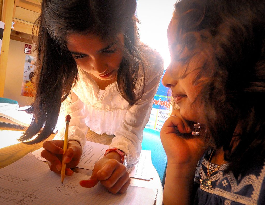 A third-grade girl tutors another girl.