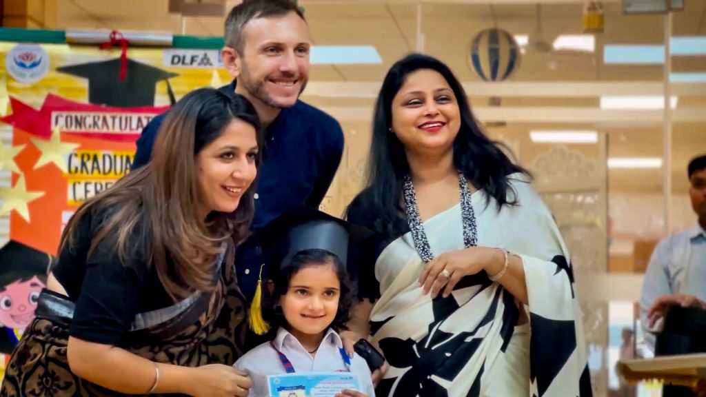 Aryavan McSweeney, director of Living Wisdom School in Palo Alto, California, poses with a parent, her enthusiastic young daughter, and her teacher during the End of Year Celebration at a DLF Foundation sponsored school in Gurugram, India.